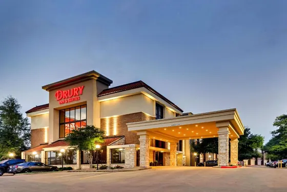 Hotel at dusk with a stone canopy and red Drury sign
