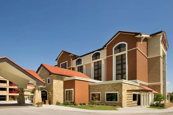 Brown and tan hotel with stone walls and red terracotta tiles