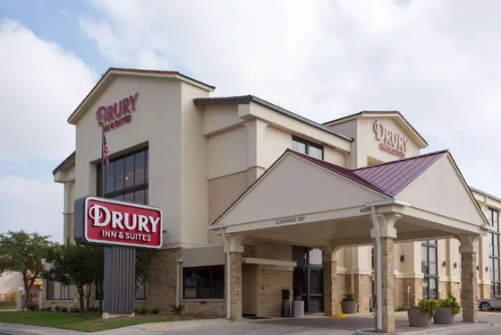 Beige hotel with a red-roofed entrance and a large red Drury sign