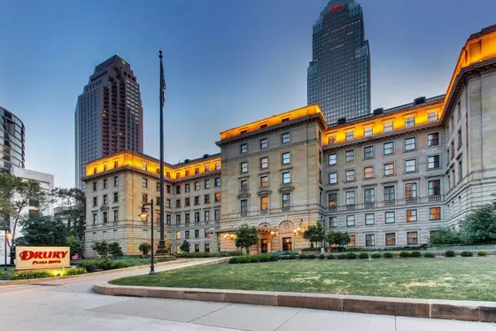 Stone hotel at dusk with lit windows and nearby towers