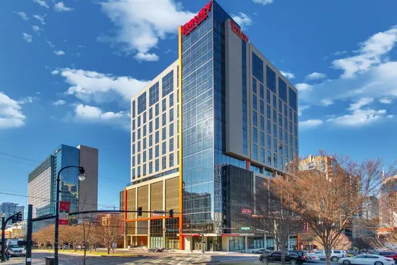 Tall glass building with a red sign on it