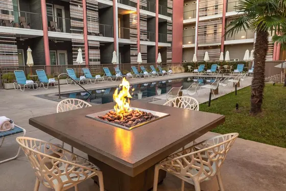 Fire pit and white chairs beside a rectangular swimming pool