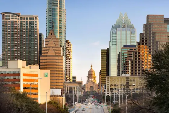 Wide street leading to a domed capitol between skyscrapers