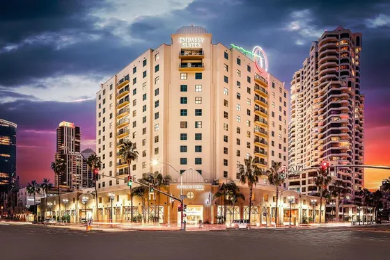 Tall building with palm trees in front of a street