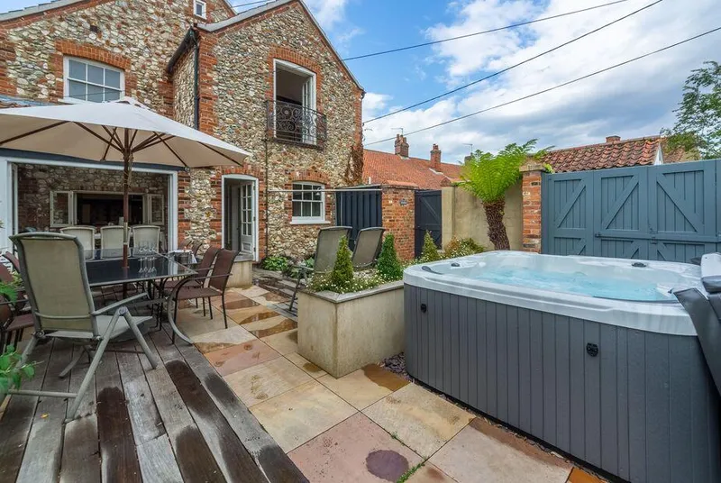 Estcourt House hot tub on sunny courtyard patio with outdoor dining