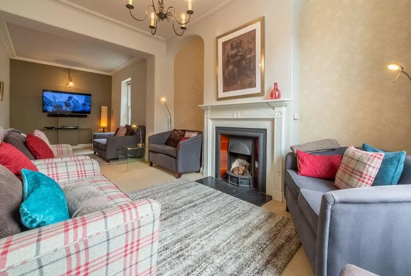 Estcourt House living room with plaid sofa and glowing fireplace