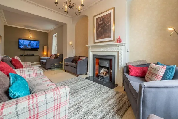 Estcourt House living room with plaid sofa and glowing fireplace