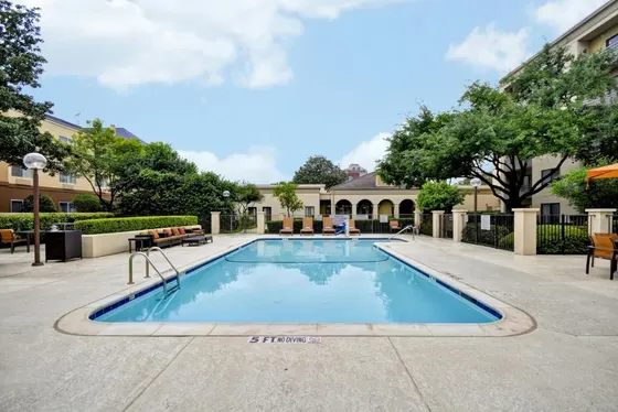 Outdoor pool with orange lounge chairs and hotel buildings