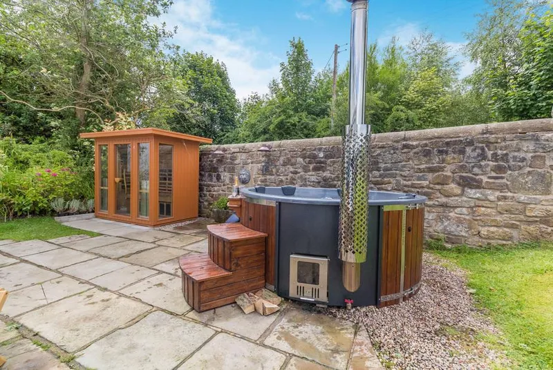 Fence House wood-fired hot tub and sauna on the stone patio