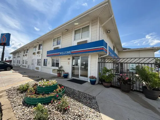Motel 6 entrance with a Welcome awning and flower pots