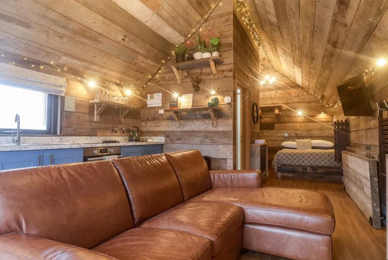 Foxes Den fairy-lit vaulted timber ceiling with leather sofa and blue kitchen