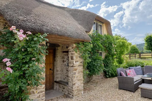 Garden View stone facade with climbing roses and thatched roof