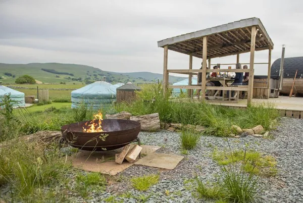 Goldfinch Yurt glamping site with fire pit and covered deck