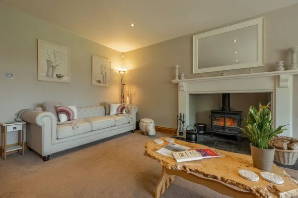 Grace Cottage Heacham living room with lit wood burner and Chesterfield sofa