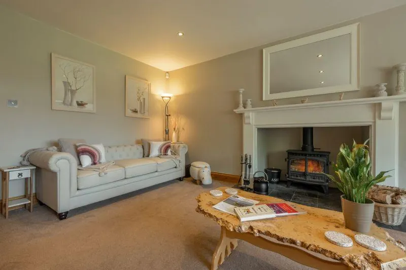 Grace Cottage Heacham living room with lit wood burner and Chesterfield sofa
