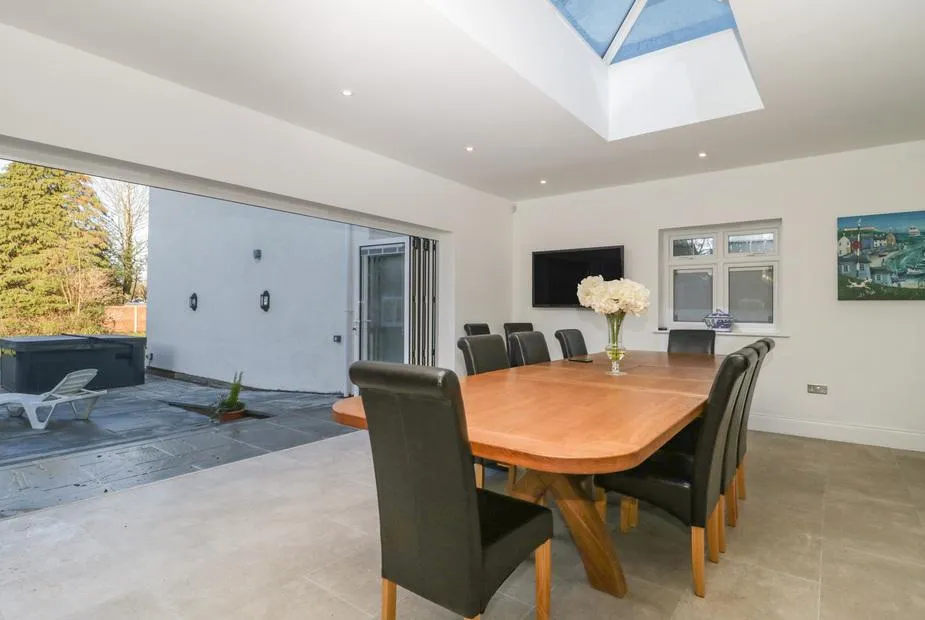 Greenlawns dining room with bi-fold doors open to patio and hot tub visible