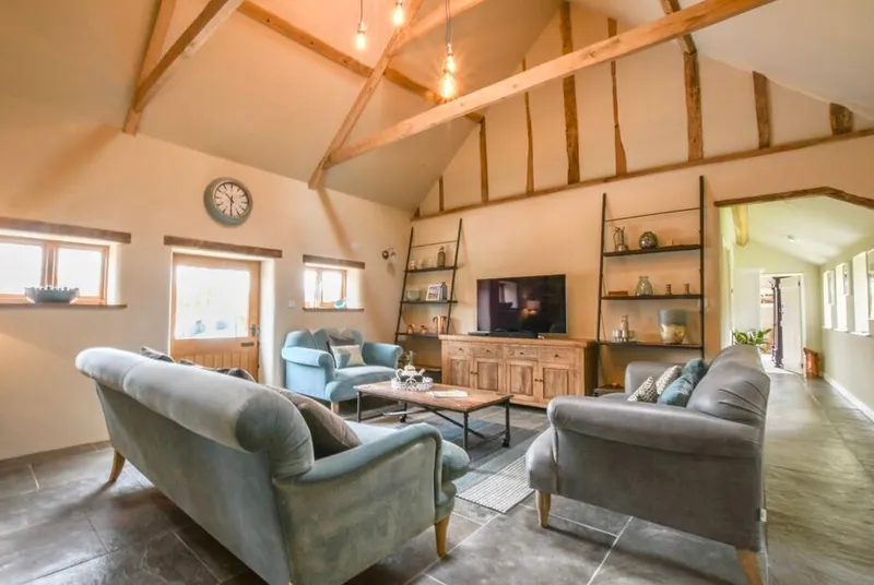 Halcyon Barn living room with vaulted beams, teal armchairs and grey sofa