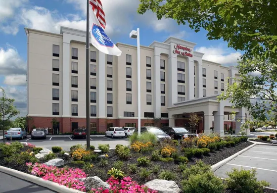 Beige and brick hotel behind a landscaped flower bed