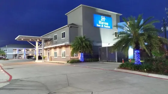 Gray hotel with a blue Haven Inn sign and lit palms