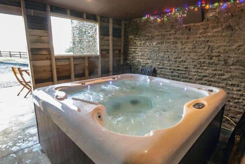 Hawthorn Cottage barn hot tub with fairy lights and window overlooking fields
