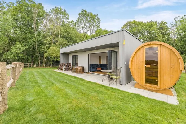 Hillview lodge and barrel sauna from garden with mature trees