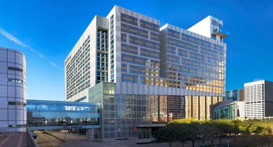 Geometric high-rise with a Hilton sign and a glass skybridge