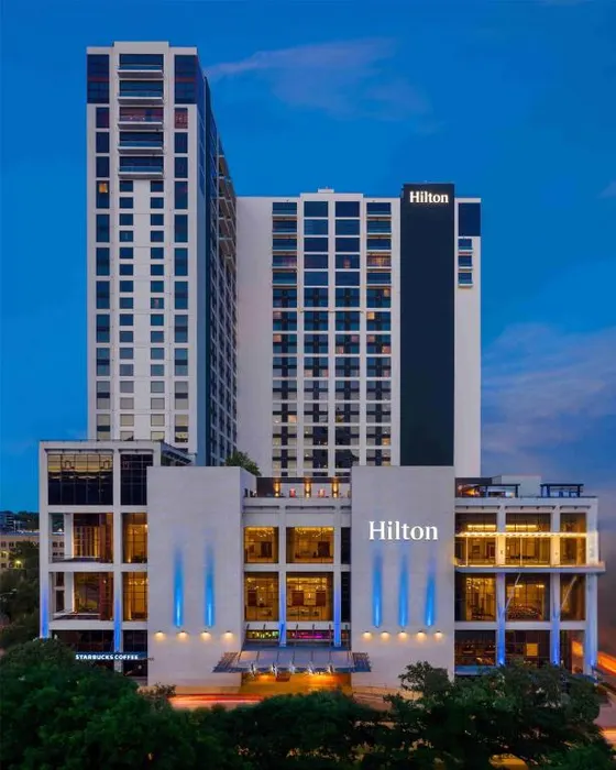 White and gray Hilton tower with blue lights at dusk