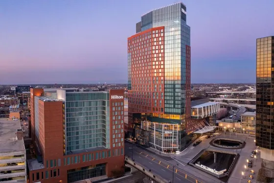 Two Hilton towers at dusk beside a city street