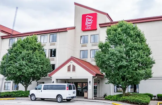 Red Roof Inn with trees and a shuttle van