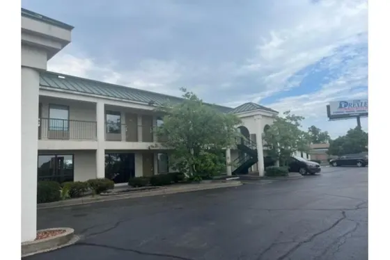 Two-story beige motel with a green roof and outdoor stairs
