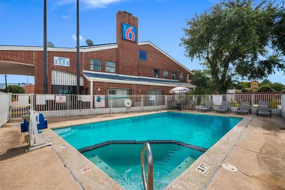 Pool and lounge chairs in front of a brick Motel 6