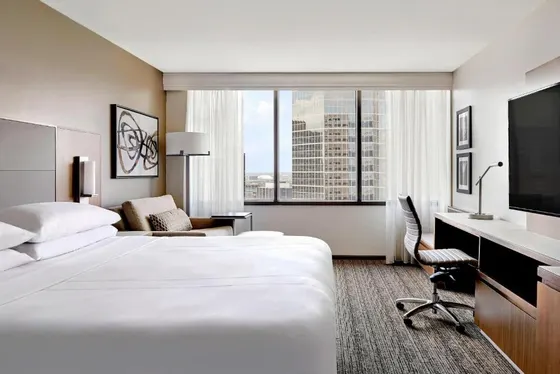 White-linen room with a desk and a city tower view