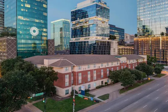 Brick hotel on a corner with glass towers behind it