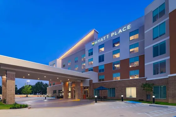 Multi-story Hyatt Place at dusk with a lit brick canopy