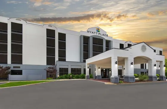 White hotel entrance canopy against an orange sunset sky
