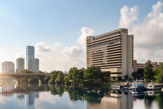 Tan Hyatt Regency on a river with a bridge and skyline