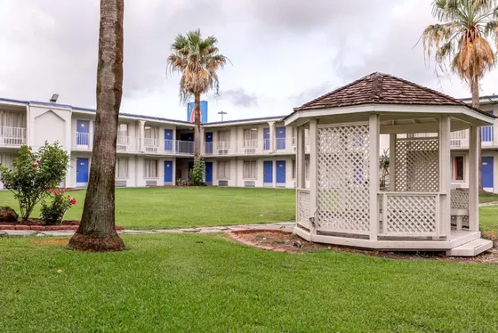 White motel with blue doors, a gazebo, and a Motel 6 sign