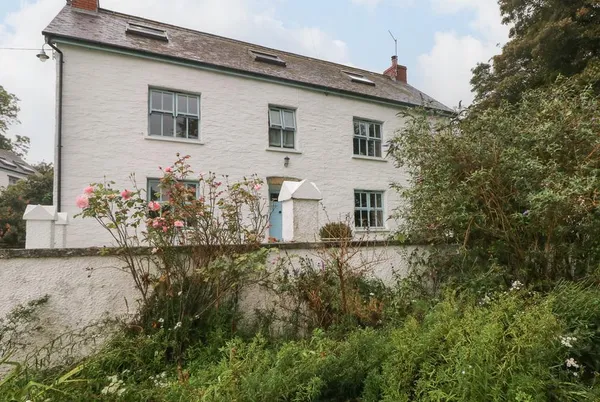 Ty Llwyd white farmhouse exterior behind cottage-garden planting