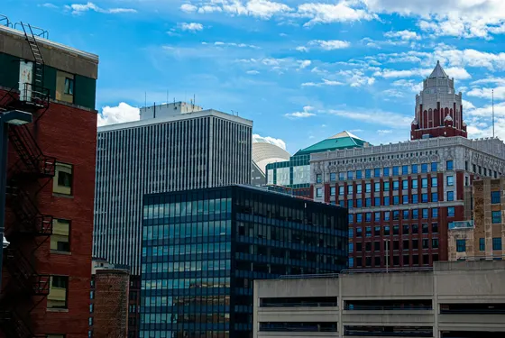 Downtown Des Moines buildings beneath a bright, cloud-dotted sky