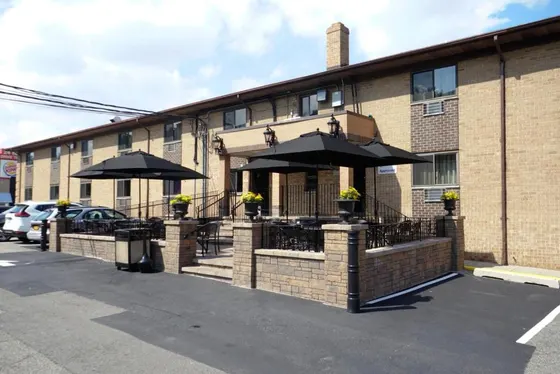 Brick hotel exterior with a furnished patio beside the car park