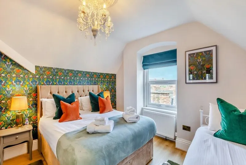 Jorvik Villas styled bedroom with floral wallpaper, chandelier and vaulted ceiling