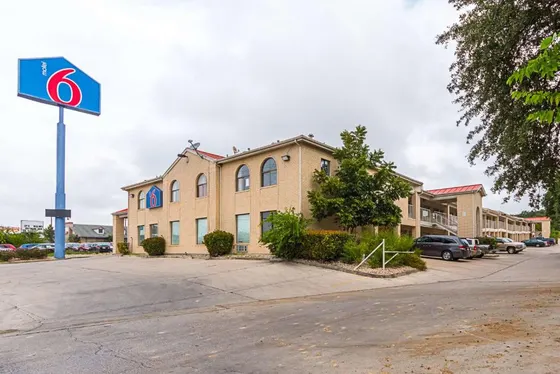 Tan brick motel with a tall blue Motel 6 sign