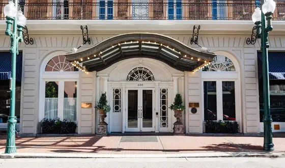 White entrance with a lit marquee and large green planters