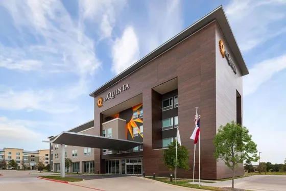 Hotel with dark wood siding, a sunburst mural, and flags