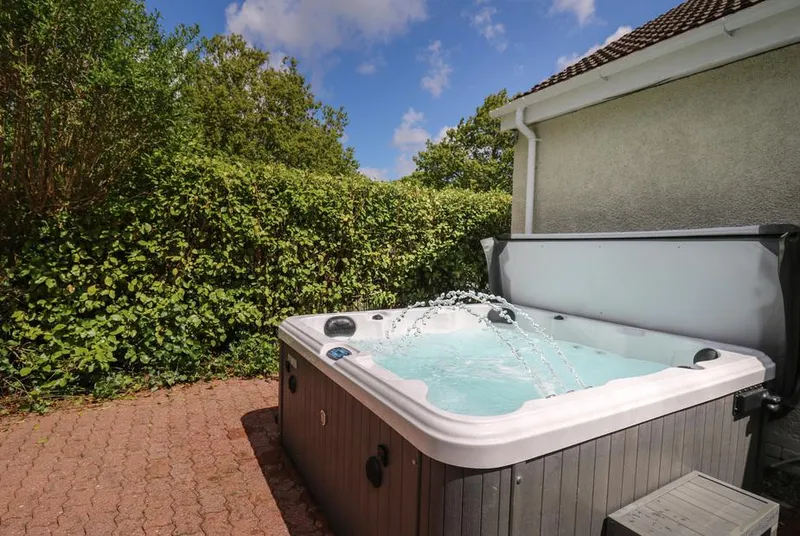 Lavender Lodge bubbling hot tub on the patio beside clipped hedges