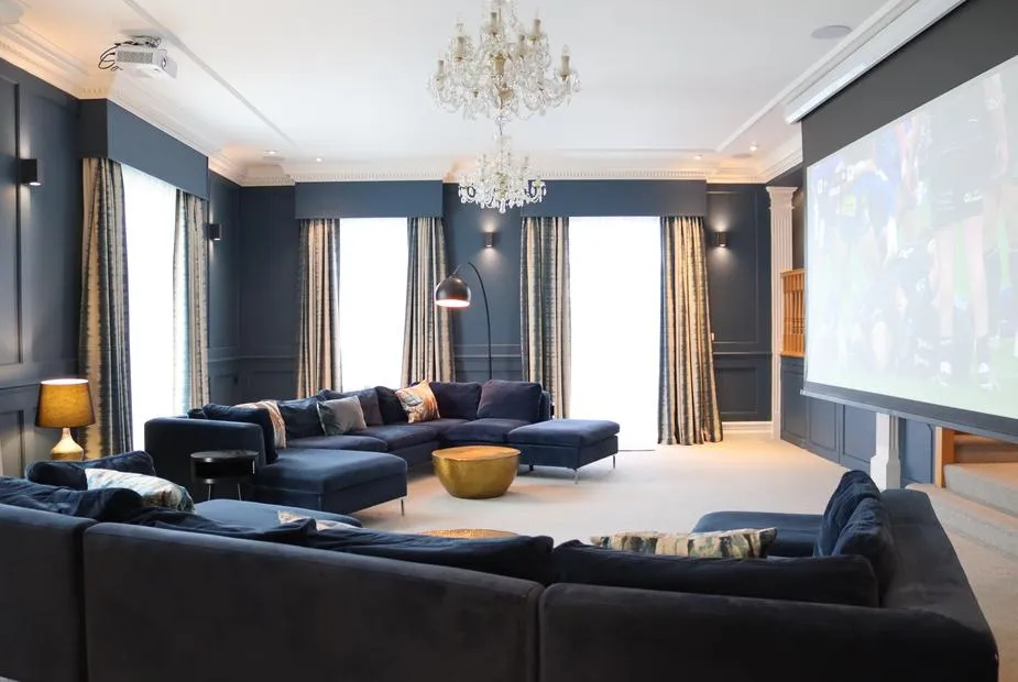 Leafield House cinema room with navy velvet sofas and crystal chandelier