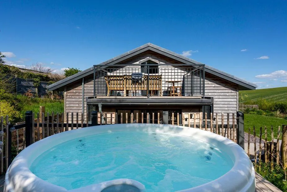 Oakwood Barn hot tub with barn and balcony behind