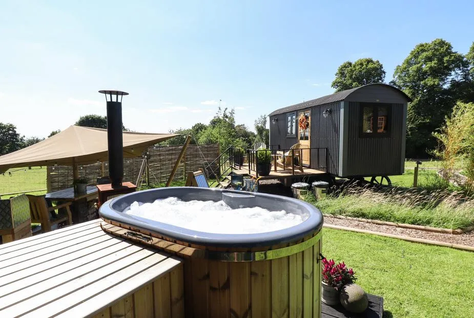 Limetree Luxury Glamping Southdown hot tub with shepherd's hut and lawn beyond