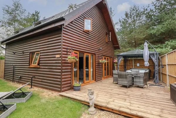 Little Lodge log cabin from garden with timber deck and lawn