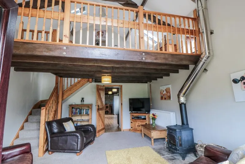 Hayloft lounge with mezzanine, beams and wood burner
